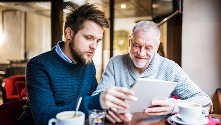 2 men sat in a cafe using a tablet